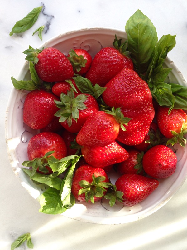 Bowl of fresh strawberries on a white table Bowl of fresh strawberries on a white table