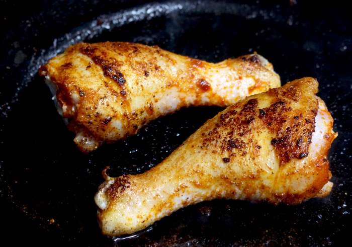 golden brown seared chicken legs in a black cast iron skillet golden brown seared chicken legs in a black cast iron skillet