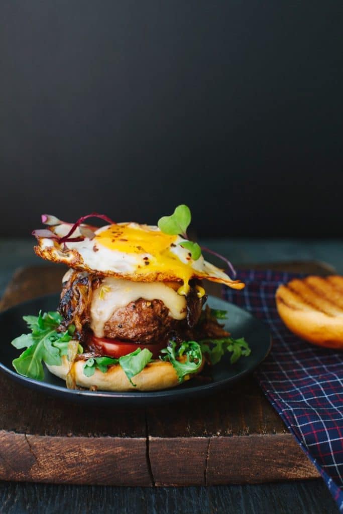 Image of Breakfast Egg Burger with Runny Yolk On a Wooden Board Image of Breakfast Egg Burger with Runny Yolk On a Wooden Board