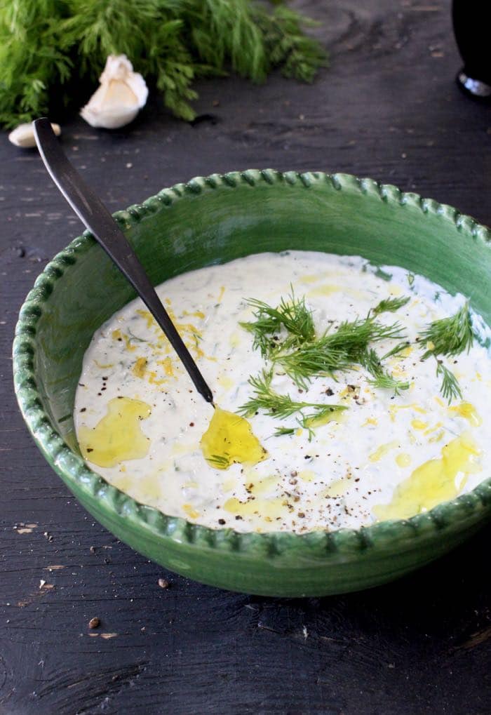 Creamy Tzatziki Sauce in a Green Rustic Bowl on a Wooden Table Creamy Tzatziki Sauce in a Green Rustic Bowl on a Wooden Table
