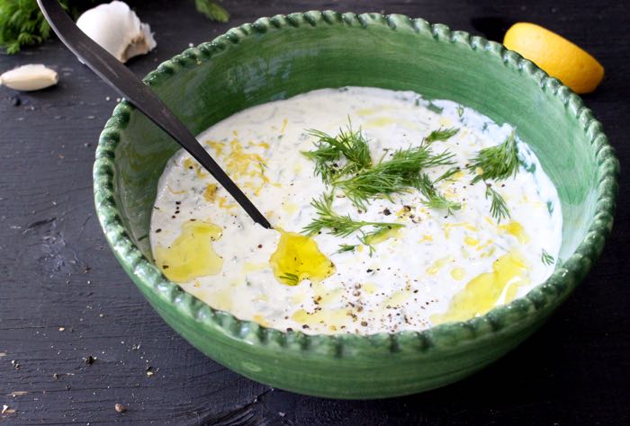 Creamy Authentic Tzatziki Sauce in a Green Rustic Bowl with Lemon Zest, Olive Oil and Fresh Dill Creamy Authentic Tzatziki Sauce in a Green Rustic Bowl with Lemon Zest, Olive Oil and Fresh Dill